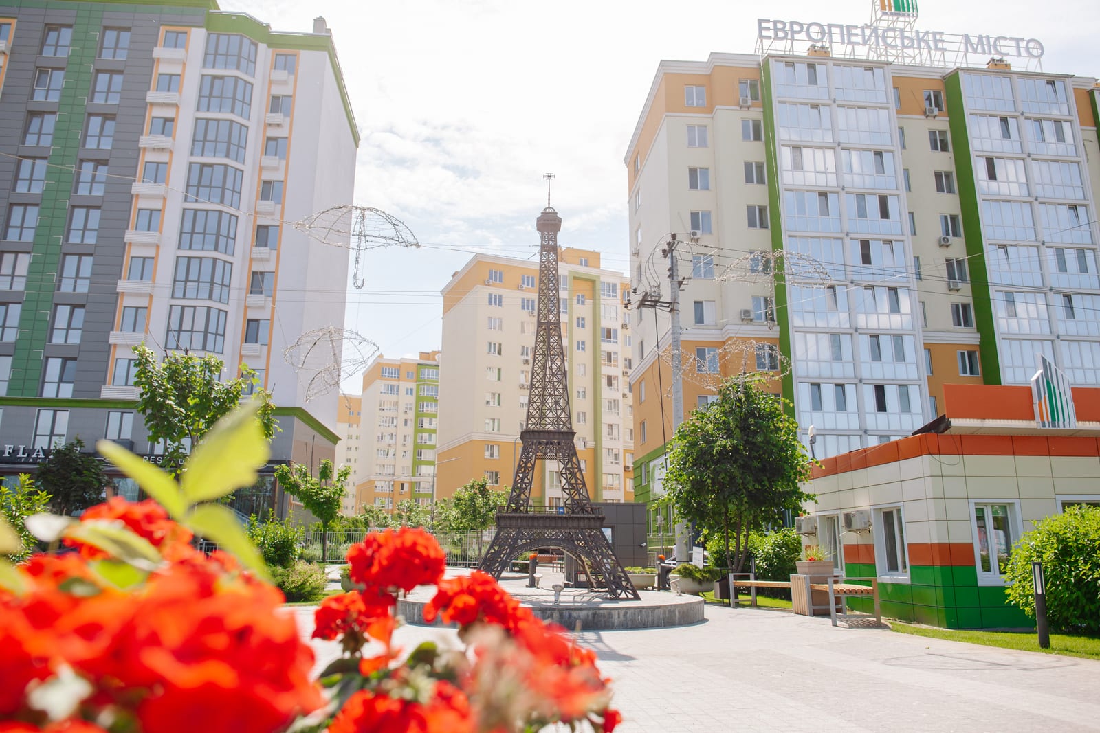 The replica of the Eiffel Tower in the courtyard of the Evromisto district by SAVO, with flowers in the foreground