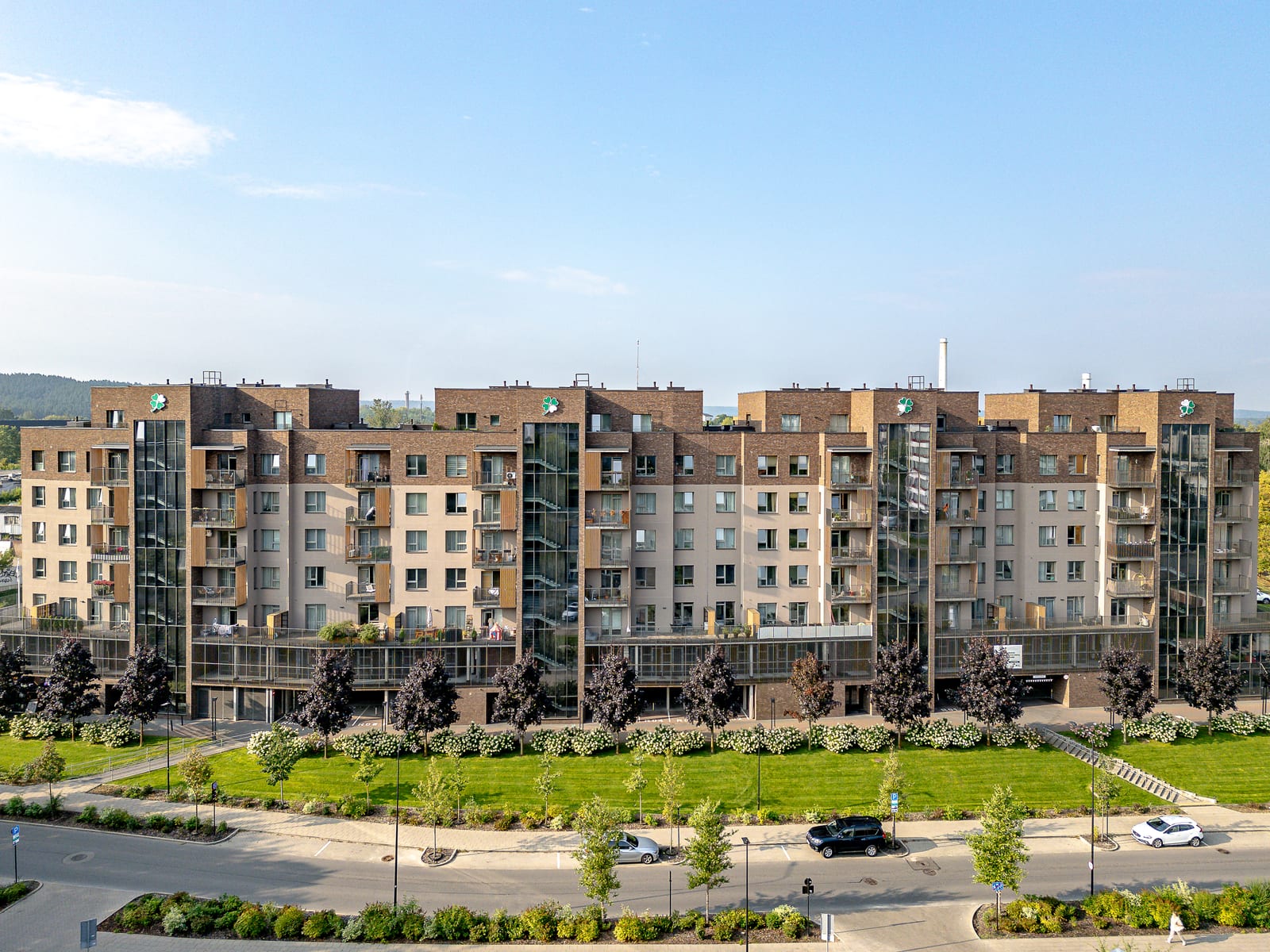 Lucky Homes by SAVO in Vilnius vanuit de lucht: de hele rij blokken in klinkerbaksteen met glazen traptorens, gazons en bloeiende hortensia's langs de straat