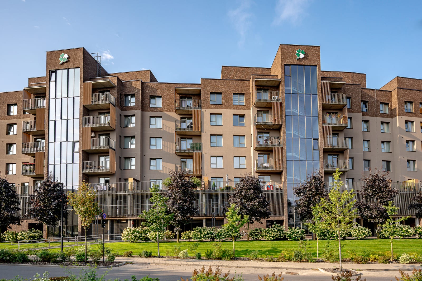 Lucky Homes by SAVO en Vilna: edificio residencial de ladrillo clínker con torres de escalera acristaladas sobre zonas ajardinadas